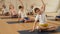 Friendly sporty family of young parents and teenage kids doing yoga together in fitness studio, sitting on mats in lotus