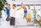 Friendly sporty parents with teen daughter and son jumping up high during dance training together in wellness studio