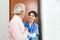 Friendly staff caregiver of nursing home talking to asian senior man in living room