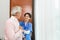 Friendly staff caregiver of nursing home talking to asian senior man in living room