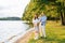 Friendly stylish beautiful family with two children standing on the shore of the lake. The girl is holding a boat. The concept of