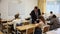 Friendly teacher man helping students during lesson in schoolroom