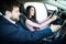 Friendly vehicle dealer showing young woman new car in showroom