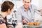 Friendly waiter offering to young female customer fresh French c