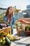 Friendly woman tending an organic vegetable stall at a farmer\'s market and selling fresh vegetables from the rooftop