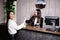 Friendly young concierge standing behind a reception counter giving room information to guest checking into a hotel