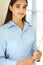 A friendly young dark hair businesswoman or female student is standing with some papers in the office