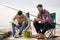 Friends adjusting fishing rods with bait on pier