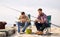 Friends adjusting fishing rods with bait on pier