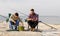 Friends adjusting fishing rods with bait on pier