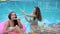 Friends in bathing suit resting in swimming-pool, summer party, girlfriends in swimsuits blow soap bubbles in poolside,