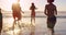 Friends, beach and people running in water for fun while on holiday at sea during sunset in bikini and swimwear outdoor