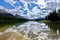 Friends in a boat on beautiful lake. Mountains and clouds reflection in calm water.