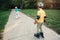 Friends boy and girl in helmets riding on roller skates in park on summer day. Sister encourage stimulate brother to ride on