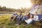 Friends on a camping trip relaxing by a tent look to camera