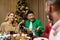 Friends celebrate Christmas eve or New Year holiday paty together sitting at the table. Feast at home group of multi