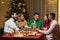 Friends celebrate Christmas eve or New Year holiday paty together sitting at the table. Feast at home group of multi