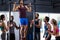 Friends cheering young man doing chin-ups