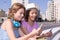 Friends with colorful clothes looking at cellphone screen in Sao Paulo, buildings and street during summer bright day light.