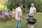 Friends cooking with the barbecue having a conversation smiling happy and laughing together talking in the patio.