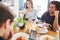 Friends eating at the table takes foodie pictures and looks on smartphone