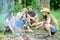 Friends group tourist relaxing near bonfire. Forest hike. Man roasting sausage while friends speak share impression and