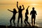 Friends, guys and girls, students are dancing at sunset background, silhouettes