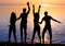 Friends, guys and girls, students are dancing at sunset background, silhouettes