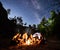 Friends hikers resting beside camp, campfire, tent at night