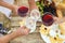 Friends holding glasses of wine over picnic table at vineyard