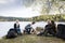 Friends Looking At Man Preparing For Bonfire On Lakeside Camping