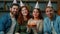 Friends in party caps celebrate festive event at home diverse multiracial people men women hold birthday cake with