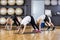 Friends Performing Downward Dog Pose In Gym