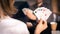 Friends are playing cards together at home. Woman is holding cards in her hands, man in the blurry background