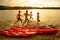 Friends Playing and Having Fun in the Water on Beach near Kayaks under the Dramatic Evening Sky at Sunset