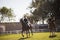 Friends riding horse at equestrian center