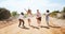 Friends, road trip adventure and desert travel holiday together laugh while walking on dirt road in summer sun. Group