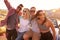 Friends On Road Trip Sitting On Hood Of Convertible Car