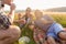 Friends sitting in grass and having burgers at barbecue party