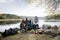 Friends Sitting On Lakeshore During Camping