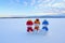 Friends snowman in red, blue, yellow hats and scarfs. Nice winter scenery with mountains, field in snow.