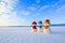 Friends snowman in red, blue, yellow hats and scarfs. Nice winter scenery with mountains, field in snow. Orange sunset background.