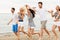 Friends in striped clothes running along beach