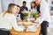 Friends in student shared flat set dining table for meal