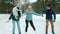 Friends teaching young woman to ice-skate in winter park but amateur falling and laughing