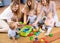 Friends with toddlers playing on the floor in sitting room