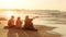 Friends two young women and man sit on tropical seaside beach at sunset and look at water. Summer trip, vacation.