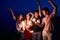 Friends walking, dancing and having fun during night party at the seaside with bengal sparkler lights in their hands