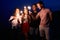 Friends walking, dancing and having fun during night party at the seaside with bengal sparkler lights in their hands