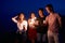 Friends walking, dancing and having fun during night party at the seaside with bengal sparkler lights in their hands